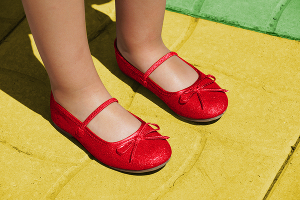 Girl with ruby red slippers on a yellow walkway.