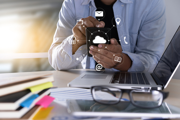 Person in front of a laptop computer using their mobile phone.